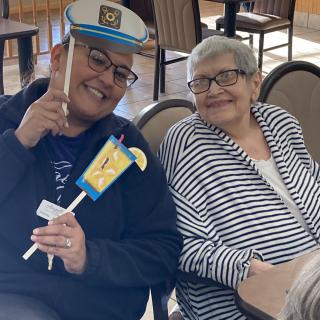 Two people smiling and posing with playful props indoors.