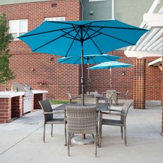 An outdoor patio area with tables and chairs under blue umbrellas.