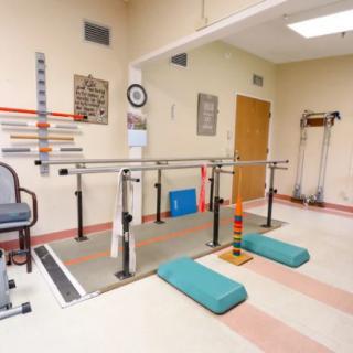 A physical therapy room equipped with parallel bars and other rehabilitation tools.