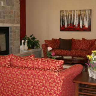 A cozy living room featuring red sofas, a stone fireplace, and wall artwork.