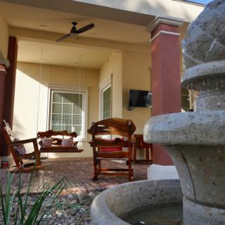 A serene outdoor patio featuring comfortable seating and a decorative fountain.