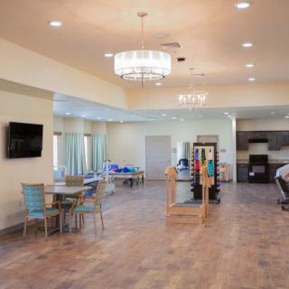 A spacious and modern living room with a chandelier, seating area, and television.