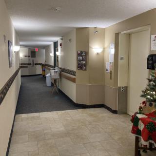 A well-lit hallway in a nursing home decorated with festive Christmas decorations.