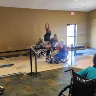 A group of elderly individuals in wheelchairs participating in a recreational activity indoors.