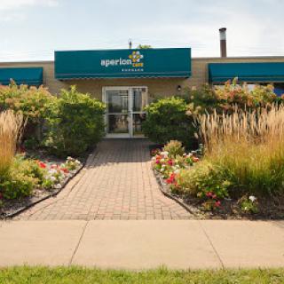 A well-landscaped entrance to a commercial building, featuring vibrant flowers and a neatly paved walkway.