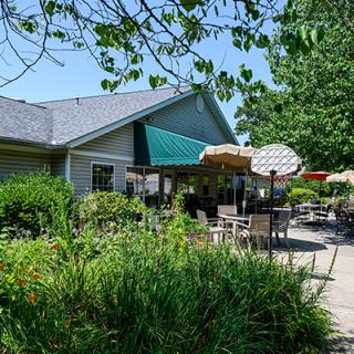 A cozy patio with outdoor seating surrounded by lush greenery on a sunny day.