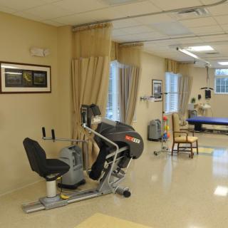 A healthcare therapy room featuring exercise equipment and seating.