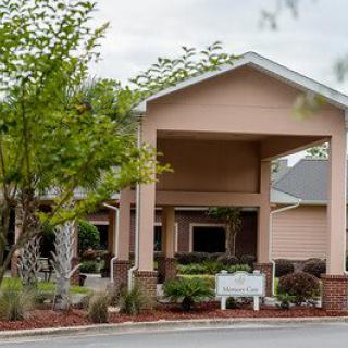 A house with a covered entrance surrounded by trees and landscaping.