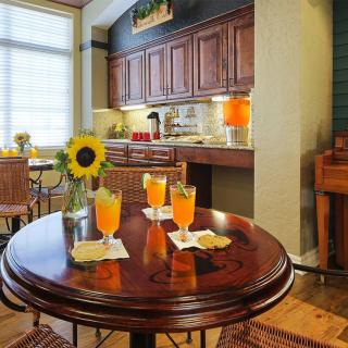 A cozy kitchen interior with a round table featuring three glasses of orange drinks and a sunflower centerpiece.