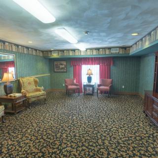 A vintage living room with patterned carpet, classic furniture, and decorative lamps.
