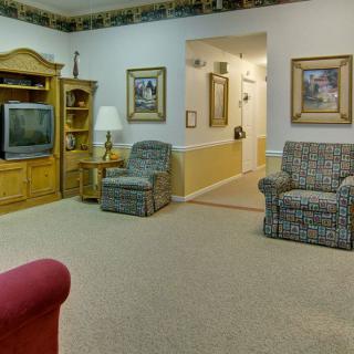 A cozy living room featuring comfortable chairs, a television, and decorative wall art.