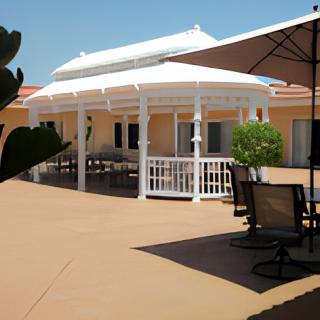 An inviting patio area featuring a white gazebo with outdoor seating under a clear blue sky.