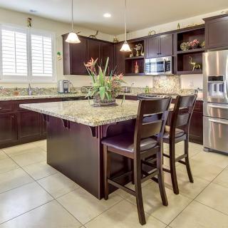 A modern kitchen with an island, granite countertops, and stainless steel appliances.