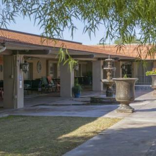 A serene courtyard featuring a fountain, surrounded by columns and lush landscaping.