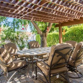 A cozy outdoor patio set under a pergola in a serene garden setting.