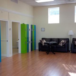 A brightly lit lounge area with colorful lockers, comfortable couches, and a wooden floor.