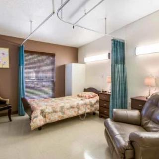 A cozy hospital room with a single bed, armchair, and warm lighting.
