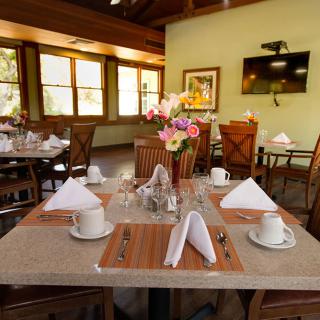 A beautifully set dining table in a cozy restaurant, featuring flowers and neatly arranged napkins.