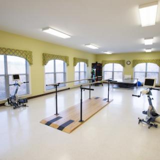 A well-lit physical therapy and exercise room equipped for rehabilitation activities.