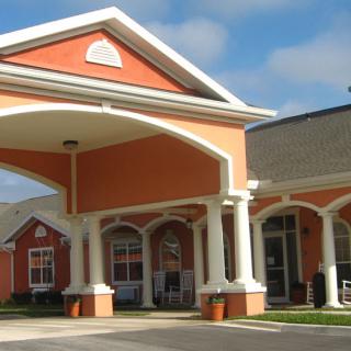 A building with a covered entrance featuring columns and a pitched roof.