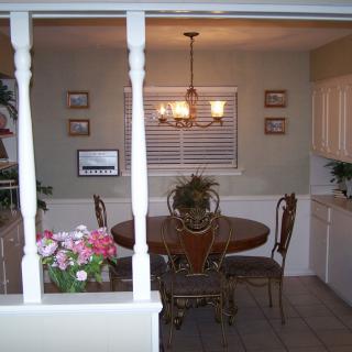 A cozy dining room with a round table, decorative plants, and a chandelier overhead.