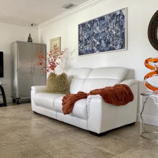 A stylish living room featuring a contemporary white sofa, artwork on the wall, and modern decorative elements.