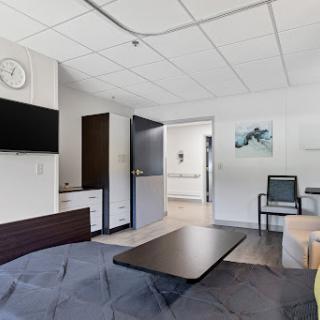 A modern hospital room featuring a bed, television, and seating area.