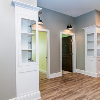 A spacious and modern interior featuring white cabinetry and wooden flooring.