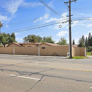 A residential building on a sunny day with visible power lines and trees along an asphalt road.