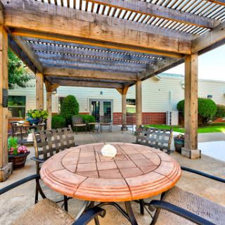A serene outdoor patio space featuring a wooden pergola and a circular table, perfect for relaxation and gatherings.