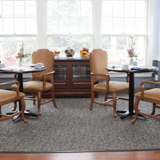 A cozy dining area featuring elegant wooden furniture, soft seating, and a bright atmosphere filled with natural light.