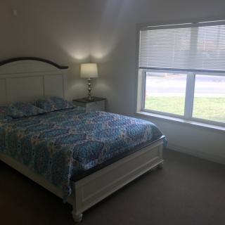 A cozy bedroom with a neatly made bed, a bedside lamp, and a large window.