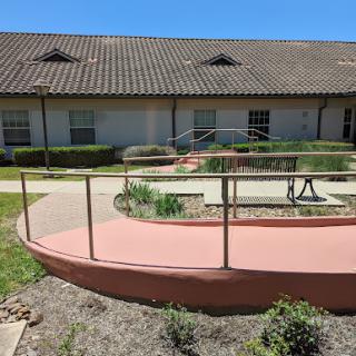 A view of a wheelchair-accessible ramp leading to a building with landscaped gardens.