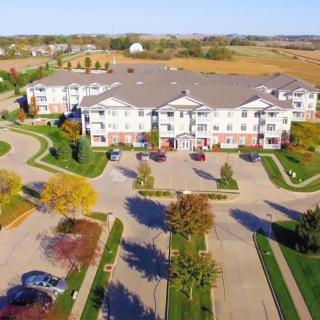 Aerial view of a suburban apartment complex surrounded by roads and autumn trees.