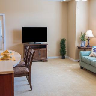A cozy living room with a sofa, television, and dining area.