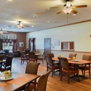 A spacious dining area featuring wooden tables and chairs, with ceiling fans and natural lighting.