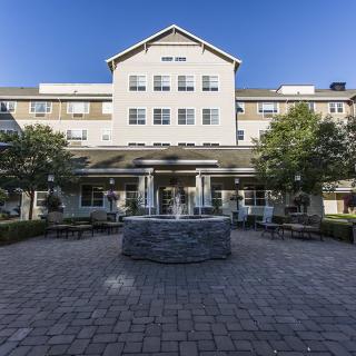 A view of a building with a courtyard and fountain in front.