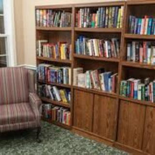 A cozy reading corner featuring a wooden bookshelf filled with books and a comfortable striped armchair.