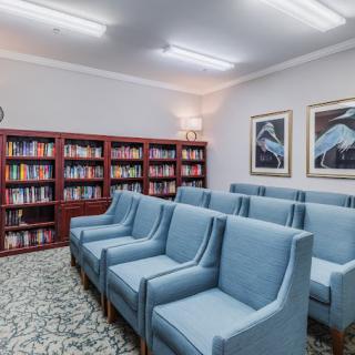 A cozy reading room with rows of blue chairs and bookshelves filled with books.