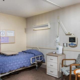 A hospital room with a bed, medical equipment, and a chair.