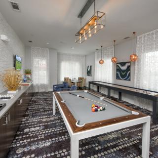 A modern game room featuring a pool table, stylish lighting, and contemporary artwork.