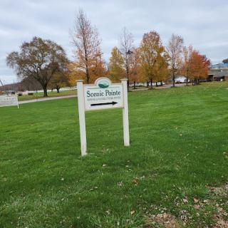A sign indicating a location in a park surrounded by autumn trees.