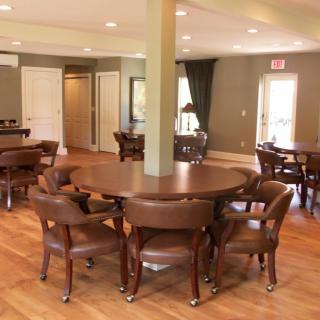 A well-lit dining area furnished with wooden tables and chairs on a polished wooden floor.