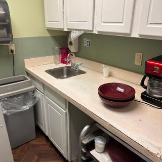 A cozy kitchen setup featuring a countertop with a sink, coffee maker, and bowl.