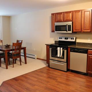 A cozy kitchen and dining area featuring modern appliances and wooden cabinetry.