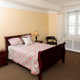 A cozy bedroom with a wooden bed frame, floral bedding, and a lamp on the nightstand.