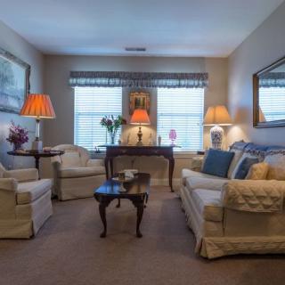 A cozy living room with comfortable sofas, armchairs, and various lamps creating a warm ambiance.