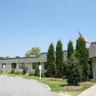 A building with a flag, surrounded by trees and landscaping under a clear blue sky.