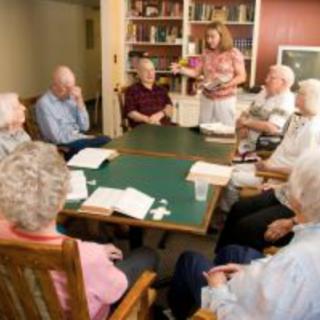 A group of seniors engaging in a book club discussion in a cozy library setting.