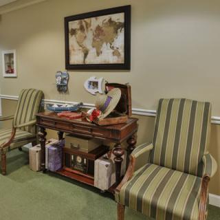 A cozy interior featuring two striped chairs and a decorative table adorned with various items and artwork on the wall.